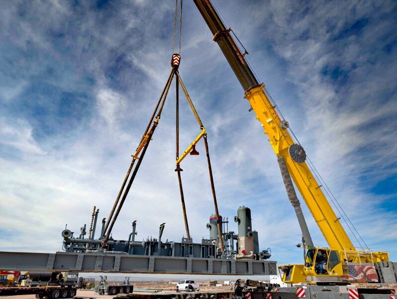 Crane lifting a process skid with a spreader bar
